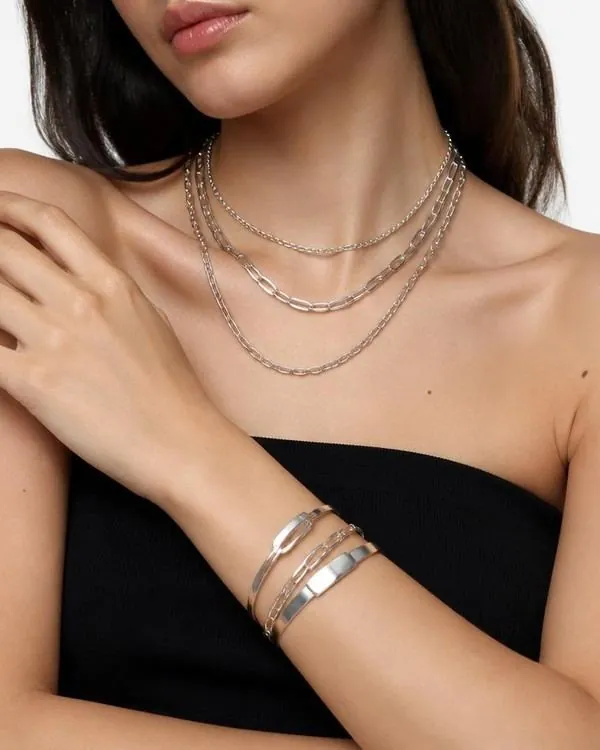 Layered silver jewelry over a black top